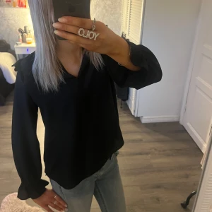svart blus med volang detaljer  - kommer tyvärr inte till användning 