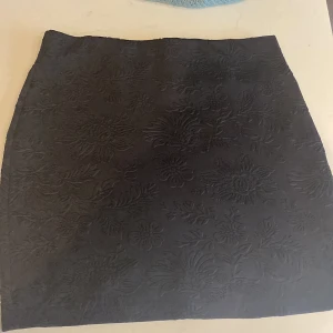 Stilig mönster kjol - Svart kjol utan några förstörelser. Fina mönster som ger mer detalj. Är i st s men skulle kunna passa  någon med st m också. 