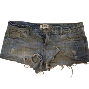 Jeansshorts från PINK Victoria secret  - Säljer ett par coola jeansshorts från PINK Victoria secret.De är slitna med fransiga kanter och har en  blå grå jeansfärg.🦄