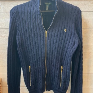 Ralph Lauren Zip  - En Ralph lauren zip tröja med krage i Använd men ganska fint skick. Mörk blå med några guldiga detaljer. Passar storlek xs men står m i den eftersom den är liten i storleken skulle säga att den passar runt 165 lång. Priset inte hugget i stenen