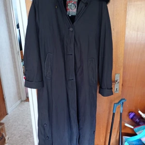 Damkappa med luva stl 44 - Fin mörkblå damkappa med luva stl 44 med päls.fodrad inne med avtagbart pälsfoder blått.knäppes med Knappar.läderdetaljer på ärmar mm.sprung bak. Mycket fint skick.inköpt hos Cassels i Kungsbacka.Märke Alexandra.