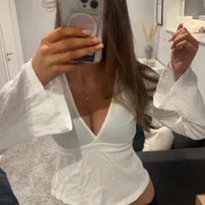 Vit topp - Säljer en superfin vit omlottopp med långa ärmar och v-ringning från Gina som man kan knyta där back.Perfekt för både vardag och fest! Den har en skön och luftig passform som gör den bekväm att bära hela dagen. Skriv privat för fler bilder eller frågor 