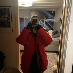 Röd vinterjacka med päls från Canada Goose - Säljer en varm och snygg röd vinterjacka från Canada Goose. Jackan har en stor huva med päls och långa ärmar. Perfekt för kalla vinterdagar! Den har dragkedja och flera praktiska fickor. Passar både till vardags och utomhusaktiviteter. Det är en äldre modell men använd lite, mestadels varit på förvaring där inget damm heller samlats. Säljer billigt pågrund av platsbrist i garderoben. 😊Storlek skulle jag säga är 34-36, vill säga xs-s. Hittar ingen vidare lapp om storlek. Hör av vid intresse!