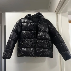 Svart pufferjacka - Säljer trendig glansig vinterjacka. Perfekt för vintern med sin varma och mysiga design. Ny utan prislapp💗Säljer även samma i vit