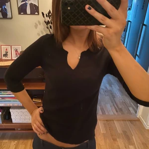 Svart blus med trekvartsärm - Säljer en snygg svart blus med trekvartsärm och v-ringning. Den har fina detaljer på ärmarna som ger en extra touch. Perfekt för både vardag och fest! Det är egentligen en klänning som jag klippt av därav slitningar längst ner på blusen😊