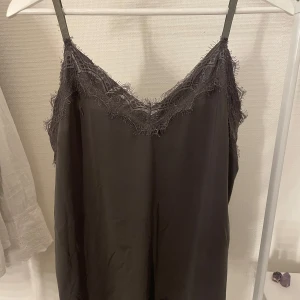 Grå spetstopp - Grå topp med spets upptill och nertill. Köpt ny på sellpy med prislapp och aldrig använd av mig. 