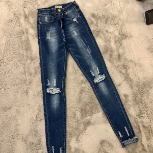 Blå skinny jeans från Blue Rags - Snygga blå skinny jeans från Blue Rags med slitna detaljer för en trendig look. De har en dragkedja och knapp framtill. Perfekta för en casual stil och passar till alla tillfällen. De är i bra skick och redo för en ny ägare!