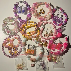 23 Färgglada armband och örhängen - Säljer ett set med färgglada armband och örhängen i olika stilar. Armbanden är gjorda av pärlor i rosa, lila, gult och blått. Örhängena har olika motiv som fjärilar, blommor och cupcakes. Perfekt för att liva upp vilken outfit som helst! 🌸