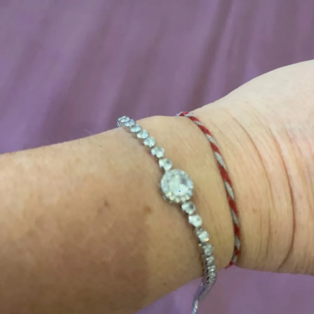 Säljer ett superfint glittrigt armband med strass. Armbandet har en rad av små, gnistrande stenar och en större sten i mitten som verkligen fångar ljuset. Perfekt för att lägga till lite bling till din outfit! Passar både till vardags och fest. 💎✨. Accessoarer.