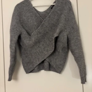 Grå stickad omlott-tröja  - Säljer en supermysig grå stickad tröja från Even&Odd. Den har en snygg omlott-design framtill och långa ärmar. Perfekt för höst och vinter när du vill hålla dig varm och stilren. Passar både till vardags och lite finare tillfällen. 🧶✨