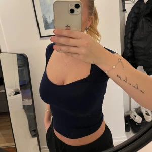 Mörkblå kortärmad topp - Snygg mörkblå topp med korta ärmar och en djup v-ringning. Använd ett få antal gånger. Köpt från nelly i storlek S. Den är väldigt stretchig så skulle kunna pass en M. Toppen är mörklblå.