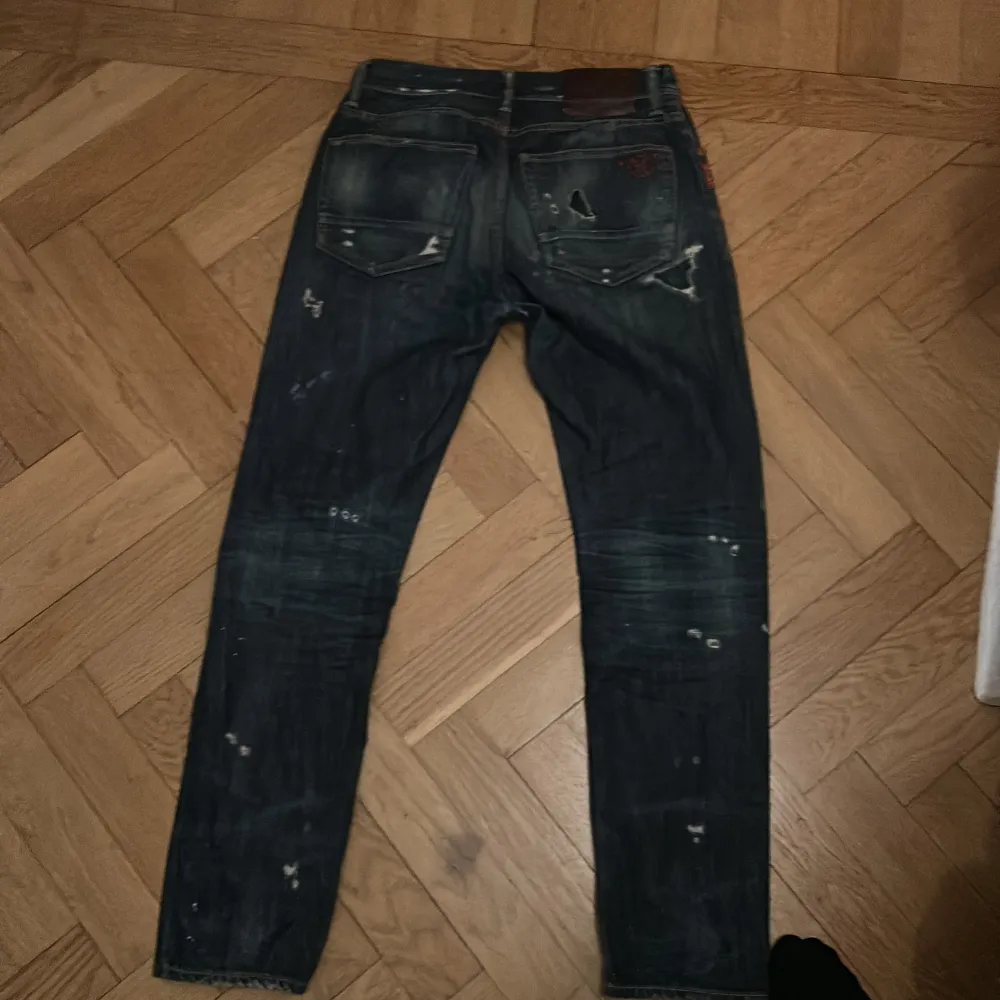 Säljer ett par mörkblå jeans från Taylor Tweed med slitna detaljer och hål för en cool, vintage look. Perfekta för en avslappnad stil. De har en klassisk femficksdesign och är i bra skick trots slitningarna.. Jeans & Byxor.