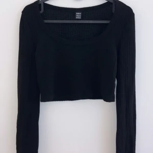 Svart ribbad croppad tröja - Snygg svart ribbad tröja från H&M i croppad modell. Perfekt för både vardag och fest! Den har långa ärmar och en rund halsringning. Passar bra till jeans eller kjol för en trendig look.