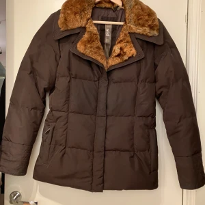 Brun dunjacka med päls - Brun dunjacka med päls som är figursydd i modell. Från Italienska märker add, nypris minst 3000-4000kr. Nästan aldrig använd så i mycket bra kvalitet. Liten i storlek.  Hemsida: https://www.add.it/en-eu/collections/womens-down-jackets?page=3