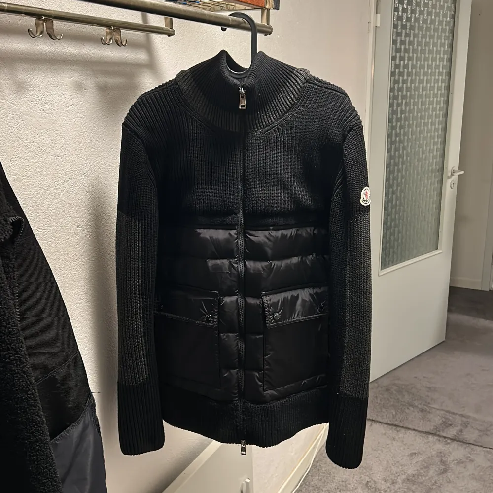 Säljer en snygg svart stickad jacka från Moncler i nytt skick. Den har en dragkedja framtill och quiltade detaljer på framsidan. Perfekt för höst och vinter med sin varma och stilrena design. Storlek M.. Jackor.