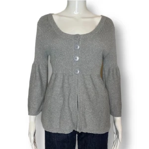 Coquette topp - Säljer en superfin grå stickad kofta med stora knappar framtill. Den har en skön passform med långa ärmar och en lätt utsvängd nederdel. Perfekt för höst och vinter, både mysig och stilren. Passar till både jeans och kjol!