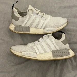 Vit/gråa Adidas NMD R1 - Superfina NMD R1 sneakers, är i fint skick och använd få gånger, säljs pågrund av att dom inte kommer till användning, storlek 42 2/3. Kontakta mig vid fler bilder eller frågor, ny pris samt det jag köpte för är 1695 säljs därför för 950kr🩷