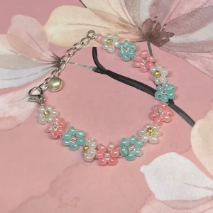 Färgglatt blommigt handgjort armband - Superfint armband med små blommor i pärlor. Det har en mix av färger som rosa, blå, vit och gul. Perfekt för att liva upp vilken outfit som helst! Armbandet har en justerbar kedja med bjällra . Passar perfekt för sommarens alla fester och tillfällen. 🌸 längd 13-17 cm