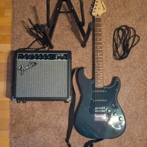 Stratocaster electric guitar pack + a stand - Squier Affinity Stratocaster HSS Pack, Charcoal Frost Metallic. Original price is 3 990,00 kr  Electric Guitar Stand by Gear4music, original price 174,00 kr  Sold with all the parts necessary so no need to buy anything extra if not needed. 