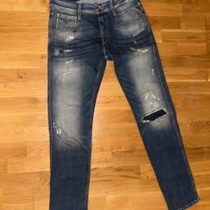 Blå jeans från Replay - Säljer ett par snygga blå jeans från Replay i bra skick. De har en cool slitningseffekt och en klassisk femficksdesign. Perfekta för en avslappnad stil och passar till de flesta tillfällen. Midjan är normal och de har en straight passform. Perfekta för både vardag och fest!