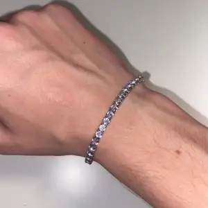 Säljer ett superglittrigt armband i silverfärg. Det är täckt med gnistrande stenar som fångar ljuset perfekt. Perfekt för att ge lite extra bling till din outfit, oavsett om det är till vardags eller fest. Längden är justerbar och det har en säker låsning. Ett måste för alla som älskar att glänsa!