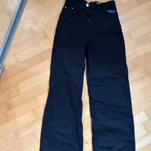 Svarta byxor - Säljer ett par svarta byxor i bra skick. De har en klassisk design med knappar och dragkedja framtill. Dem är wide leg