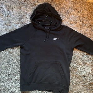 Svart hoodie från Nike - Säljer en klassisk svart hoodie från Nike i storlek S. Den har en bekväm passform med en känguruficka framtill och en justerbar huva med dragsko. Perfekt för både vardag och träning. Den är knappt använd så är i ett perfekt skick 🎀