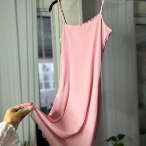 Rosa axelbandslös klänning - Säljer en superfin rosa klänning med smala axelband. Den är perfekt för sommardagar eller som en söt underklänning. Funkar även som en nattklänning. Materialet är mjukt och bekvämt med en gullig design🩷
