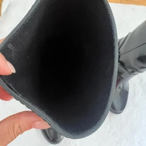 Svarta stövlar från Michael Kors - Snygga svarta stövlar från Michael Kors i nyskick. De är gjorda av ett glansigt syntetmaterial och har en stilren design med MK-loggan på sidan. Perfekta för höst och vinter, och de ger en elegant touch till vilken outfit som helst.