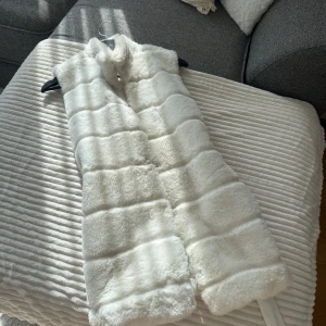 Vit väst - En falsk pälsväst som är väldigt fin förutom lite smink högst upp vid kragen, går säkert bort vid tvätt.