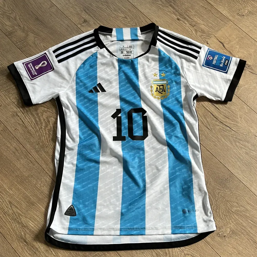 Säljer en Argentina fotbollströja från Adidas med nummer 10 och namnet Messi på ryggen. Tröjan har de klassiska blå och vita ränderna och är kortärmad. Skicket är 9/10 i stl Xs men passar även S. Stilren och passar alla fotbollsfans! . Sportswear.