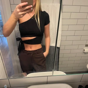 Svart oneshoulder topp - Säljer en superfin svart oneshoulder topp som är perfekt för fest! Den är croppad och har en snygg knytning i midjan 🤍