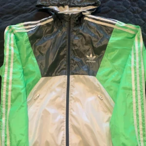 Adidas löparjacka - Adidas löparjacka med luva, vit/grå/neongrön. Bra skick, kan tvättas om du vill ha nyskick. Använd 1-2 månader. Nypris 899kr.
