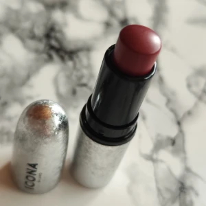 Rött läppstift från Icona Milano - Säljer ett snyggt läppstift från Icona Milano. Läppstiftet har en elegant silverfärgad hylsa som ger en lyxig känsla. Perfekt för att ge dina läppar en djärv och sofistikerad look. Använd det för en kväll ute eller när du vill känna dig extra glamorös!