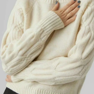 Vit stickad tröja med flätmönster - Säljer en supermysig vit stickad tröja med mönster på ärmarna.  Tröjan har långa ärmar och ribbade muddar vid ärmslut och nederkant. 