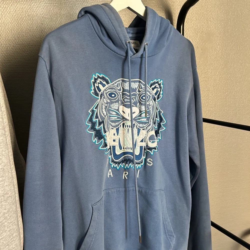 Blå Kenzo hoodie, extremt skön inför början på vintern. Den är använd men i ett väl bevarat skick somsagt. Färgen är inte exakt som när den köptes men inget som syns på håll eller vid användning. Storlek M men sitter som en lite större S.. Hoodies.