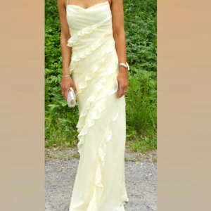 Gul bröllopsklänning med volanger  - Säljer denna otroligt vackra långklänning med volanger. Den är endast använd en gång och är väldigt bra skick. Storlek 36. Pris 750.