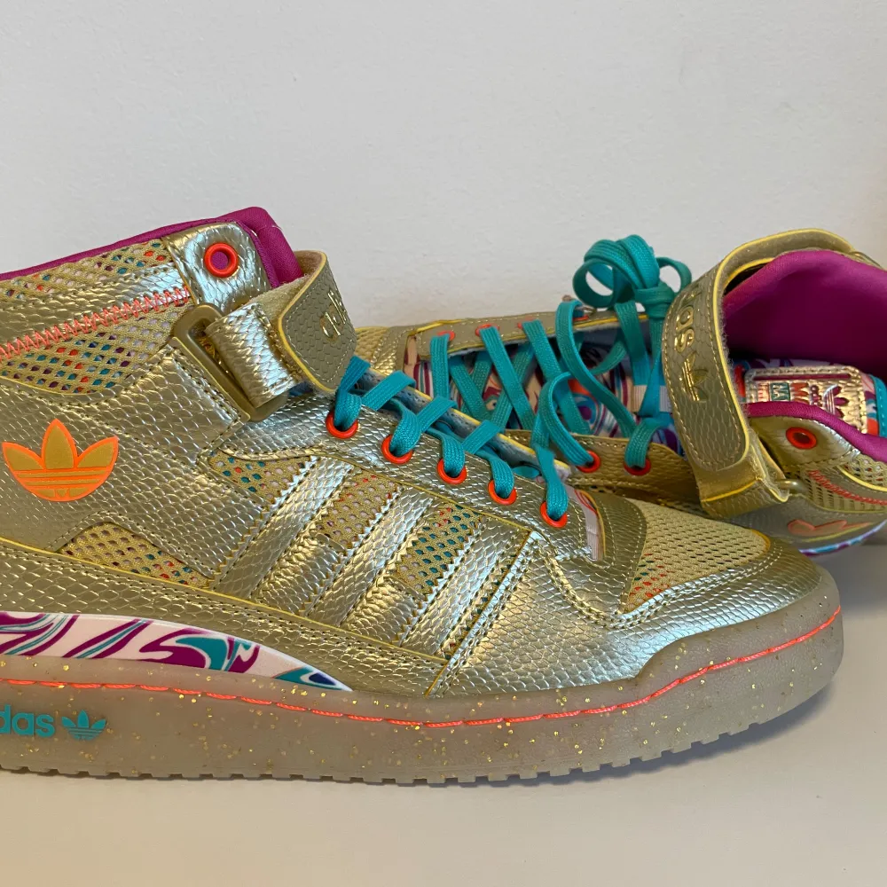 Oanvända Adidas Forum Mid Carnival i guld med flerfärgade detaljer. Inköpta i USA, storlek 9. Skor.