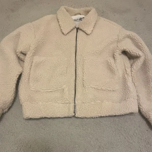 Beige teddy jacka  - En mysig jacka med fleece/teddymaterial. Den har fickor framtill och dragkedja. Ljus beige. Bra kvalité och inte tecken på användning. Storlek 158/164 men är lite stor i storleken och passar XS/S. 🧸😍