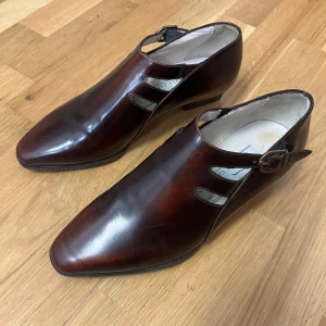 Bruna skinnskor vintage oanvända made in Italy - Snygga bruna skinnskor från Gabriele Carpigiani i italiensk design. Skorna har en elegant spetsig tå och en stilren spänne på sidan. Perfekta för både formella tillfällen och vardagsbruk. Tillverkade i Italien med högkvalitativt läder.