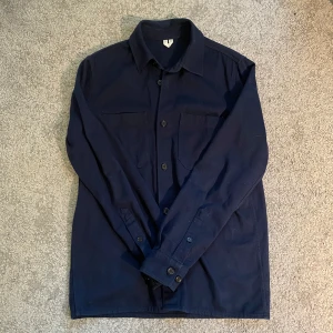 Arket overshirt - Säljer en marinblå overshirt från Arket, storlek M i nyskick. Plagget har knappt använts.  Mått: Total längd - 74cm Bröstvidd - 51cm Axelbredd - 44cm Arminnerlängd- 49cm
