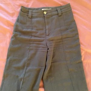 Svarta kostymbyxor från Zara - Säljer ett par stilrena svarta raka kostymbyxor från Zara. De har en klassisk design med knapp och dragkedja framtill. Perfekta för både jobb och festliga tillfällen. Byxorna är i bra skick och har en elegant passform.