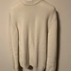 Vit ribbad tröja från These Glory Days - Säljer en stilren vit ribbad tröja med långa ärmar. Perfekt för kyligare dagar och enkel att matcha med olika outfits. Tröjan har en klassisk design med rund hals och ribbade muddar vid ärmslut och nederkant. Storlek S.
