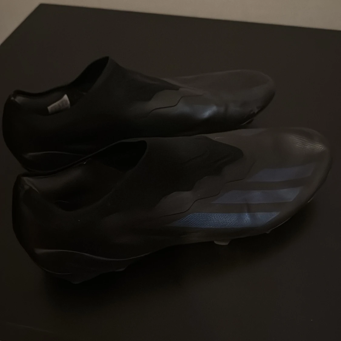 Svarta fotbollsskor med blå detaljer