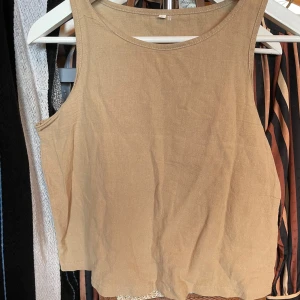 Beige ärmlös linnetopp - Säljer en stilren beige ärmlös linnetopp. Perfekt för varma dagar med sin lätta och luftiga design. Toppen har en enkel och klassisk stil som passar till många olika outfits.