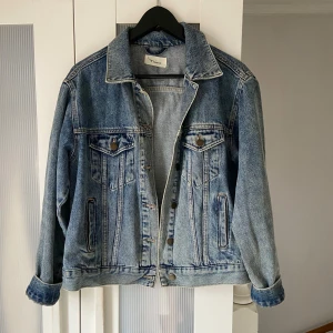 Blå jeansjacka från Twintip - Säljer en klassisk blå jeansjacka från Twintip. Jackan har en oversize passform med knappar framtill. Perfekt för en avslappnad stil.