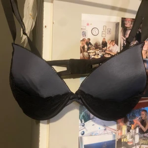 Svart spets-bh från Wonderbra - Säljer en svart bh från Wonderbra med spetsdetaljer. Den har justerbara axelband och en klassisk knäppning bak. Perfekt för att ge extra stöd och en fin siluett. I bra skick 