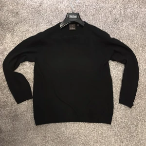 Svart tröja från Oscar Jacobson - Säljer en stilren svart tröja från Oscar Jacobson, tillverkad i Italien. Tröjan har en klassisk design med långa ärmar och rund halsringning. Perfekt för en elegant och tidlös look. Säljer då den är för liten för mig