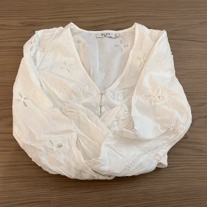 Vit blus från Na-kd - Jätte fin blus med blommdetaljer. Denna är i nyskick då ja inte använt den. Den är även v ringad och har söta knappar💕lägger ut då den är för liten🤍