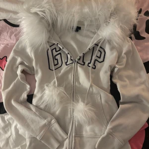 Gap hoodie med fusk päls - Såå fin gap hoodie med päls på sydd av mig. Själva hoodien är en aning miss färgad men verkligen inget man tänker på! Pälsen är helt ny. Jag har målat om dragkedjan så skriv om ni behöver bild på det.(den hade blivit grå aktig så målade den vit) storlek S men skriv till mig innan om ni vill att jag syr in den lite för att sitta tajtare❤️ jag har storlek xxs så den passar inte mig jätte bra, men skriv om ni vill ha fler bilder!💕